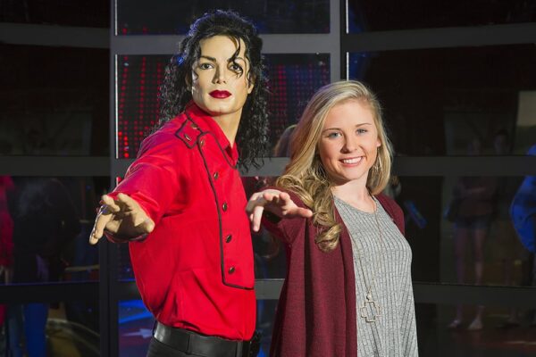 Image of female teen standing next to wax image of Michael Jackson dancing in a set pose