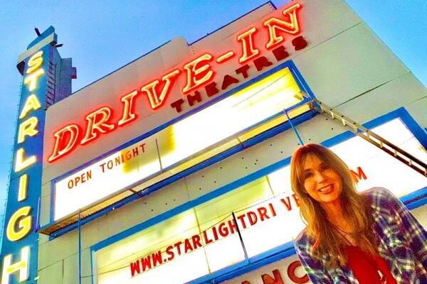 Picture of Stephanie Stuckey in front of a drive inn movie theater sign at night