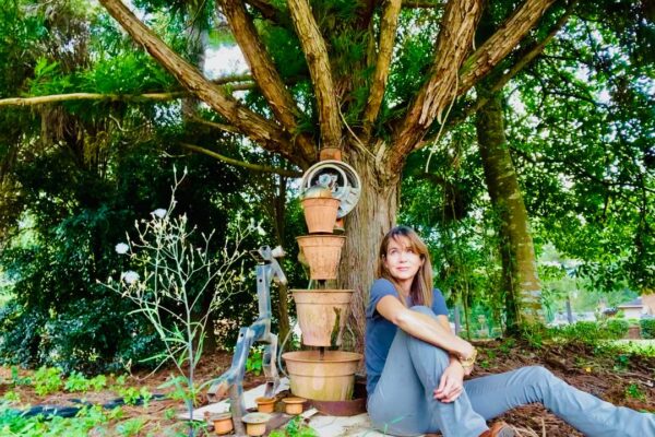 Stephanie Stuckey pondering pecans outside leaning against a tree
