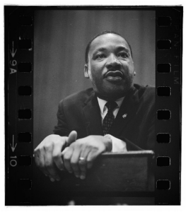 Black and white close up photo of Martin Luther King leaning over a podium.