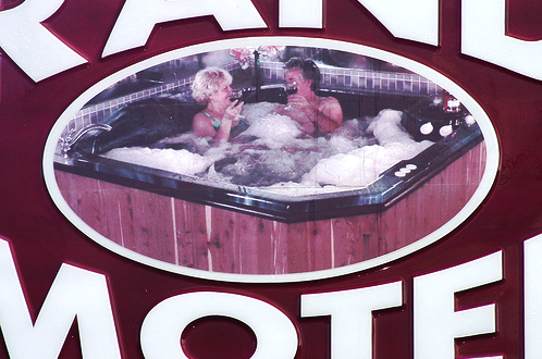 Closeup of rand Motel sign featuring a couple drinking champagne in a hot tub.