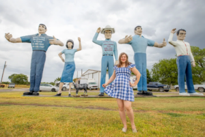 Photo of Writer and Road Tripper Valerie Bromann posing with Glenn Goode's Big People near Gainesville, Texas.