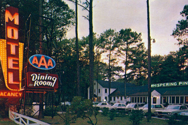 Picture postcard of exterior of Accomac, Virginia's Whispering Pines Motel and Restaurant and neon sign in front.