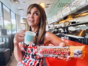 Stephanie holding a Stuckey's cup and a Stuckey's pecan log roll.