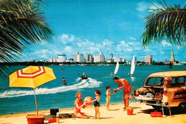 Photo Postcard of a family having fun in Florida on beach with the Miami skyline in the background, Public Domain.