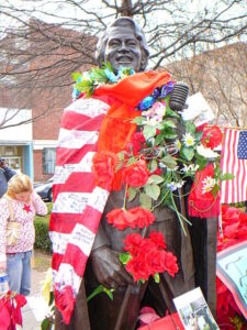 Statue of James Brown decorated with the American flag and roses.